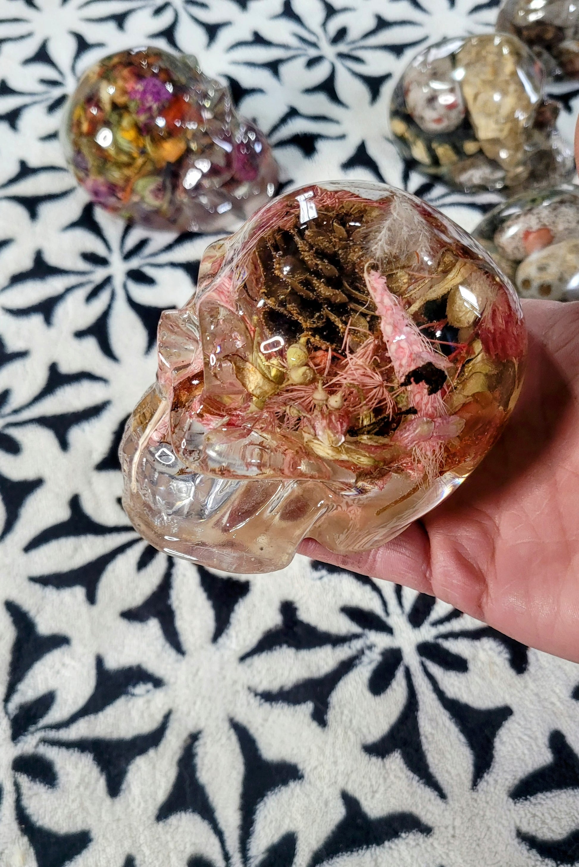 "Close-up of pink resin skull with natural pinecones and botanical accents"