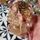 Pink resin skull encapsulation with pinecones and botanicals in crystal-clear resin