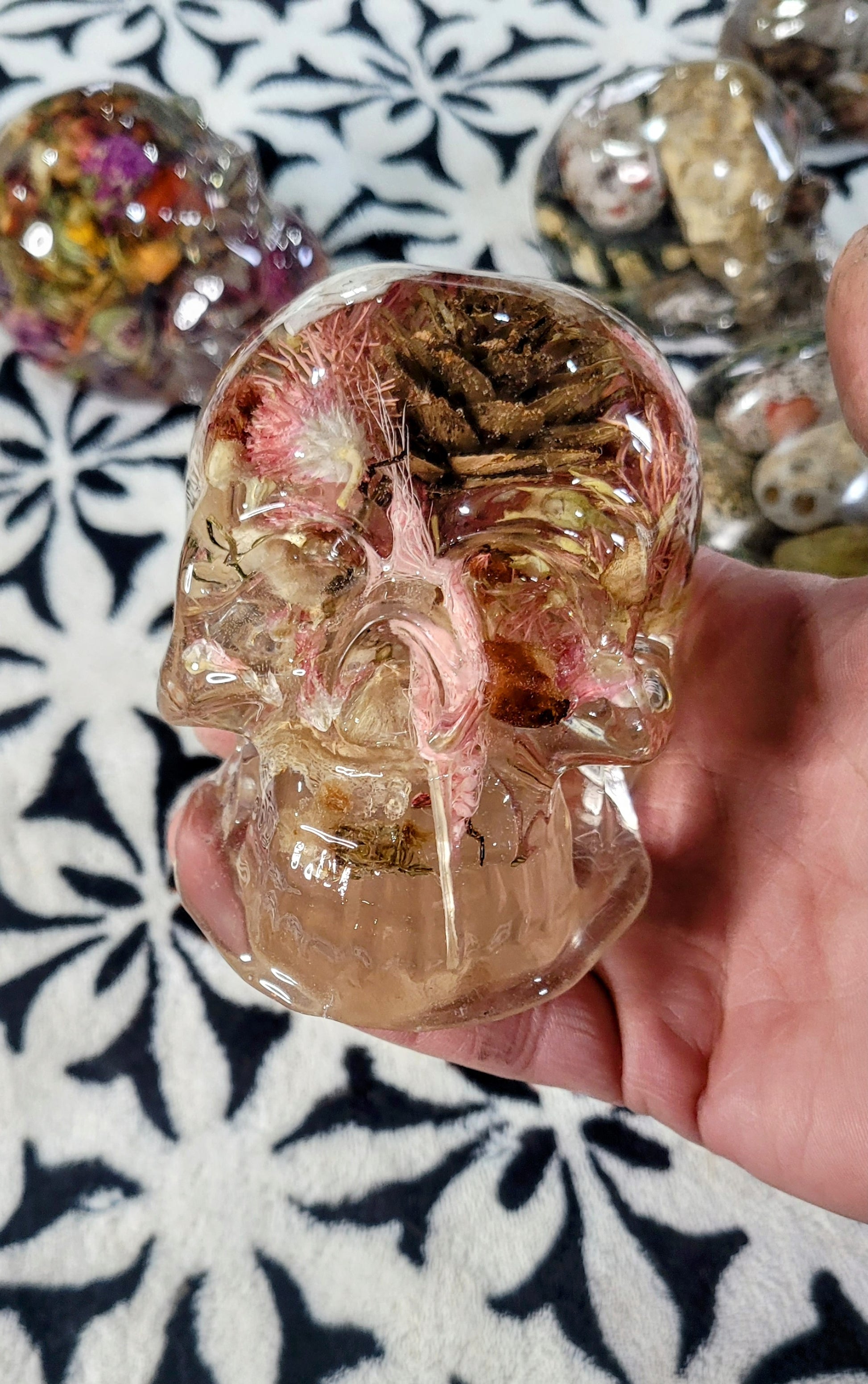 Pink resin skull encapsulation with pinecones and botanicals in crystal-clear resin