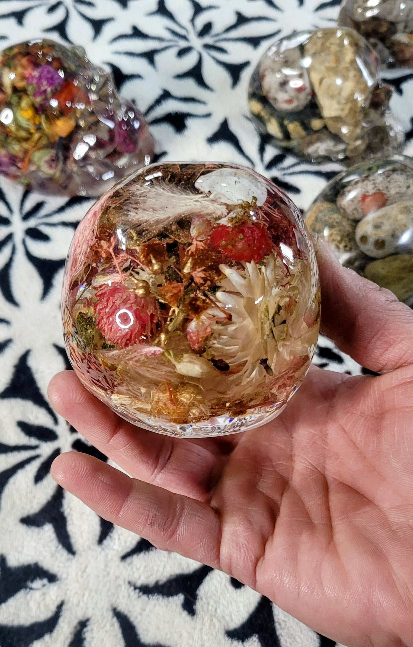 Top view of pink resin skull surrounded by preserved pinecones and flowers